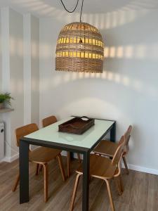 a dining room table with chairs and a light fixture at Piso en el corazón de Baiona con vistas al mar in Baiona