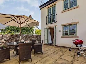 a patio with a table with an umbrella and a grill at 3 Bed in Watchet oc-83532 in Watchet