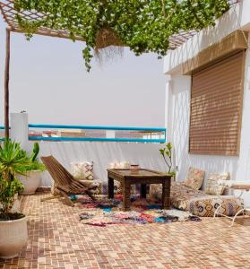 a patio with a table and a chair and a couch at Adrenalin Surf House in Tamraght Ouzdar