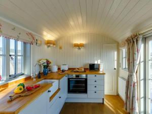 a kitchen with white cabinets and wooden floors and windows at 1 Bed in Rhayader oc-90277 in Saint Harmon