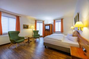 a bedroom with a bed and two chairs and a desk at Hotel Fürstenhof in Rathenow