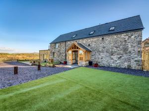 a stone barn with a green lawn in front of it at 4 Bed in Denbigh oc-76475 in Llannefydd
