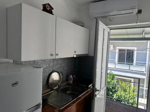 a kitchen with white cabinets and a sink and a window at Emy's Rooms in Himare