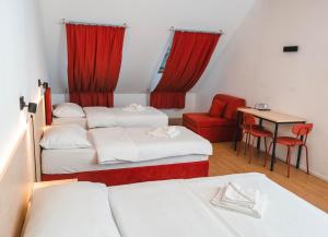 a room with three beds and a table and a red chair at Bed and Breakfast Portal in Ljubljana