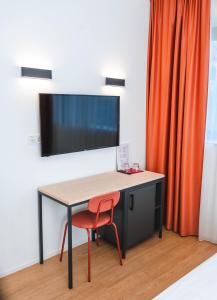 a desk with a chair and a television on a wall at Bed and Breakfast Portal in Ljubljana