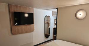 a bedroom with a tv and a mirror on the wall at Campanile Lille Sud - Douai Cuincy in Cuincy