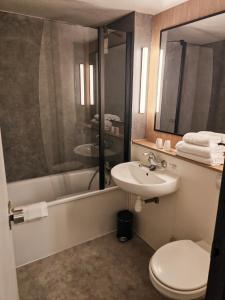 a bathroom with a sink and a toilet and a tub at Campanile Lille Sud - Douai Cuincy in Cuincy +20 photos
