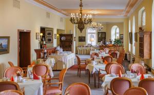 a dining room with tables and chairs and a chandelier at Hotel Fürstenhof in Rathenow
