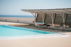 a swimming pool with chairs and a pavilion at Villa Aries - Rural Chic Experience in Gela