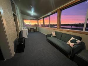a living room with a couch and a large window at Railway Hotel Greymouth in Greymouth
