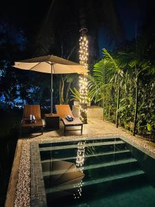 a pool with two chairs and an umbrella next to a pool at Colonial Boutique Villa Kandy in Kandy