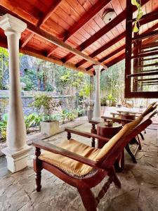 a patio with chairs and tables and a roof at Colonial Boutique Villa Kandy in Kandy