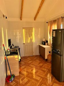 a kitchen with a black refrigerator and a wooden floor at Katarina Logde en la naturaleza in Tongoicillo