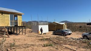 a person standing next to a house and a car at Katarina Logde en la naturaleza in Tongoicillo