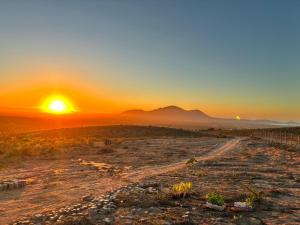 a sunset in the desert with a dirt road at Katarina Logde en la naturaleza in Tongoicillo +3 photos