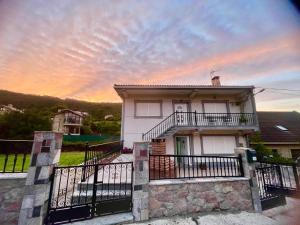 a house with a balcony with a sunset in the background at O Fogar da Fonte in Cee