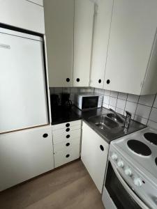 a kitchen with white cabinets and a sink and a stove at Cozy studio with a good location in Lappeenranta