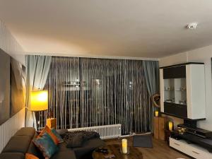 a living room with a couch and a large window at Sofias Alpenpanorama inkl Aktivcard Bayerischer Wald in Freyung