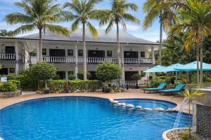 ein Swimmingpool vor einem Resort mit Palmen in der Unterkunft Hotel Chateau St Cloud in La Digue