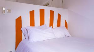 a white bed with orange and white pillows on it at Residence Mamie Léo in Abidjan