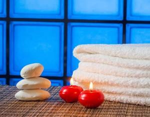 a stack of towels with two tomatoes and a candle at 4 Seasons Island Suites Athens Airport in Markopoulo