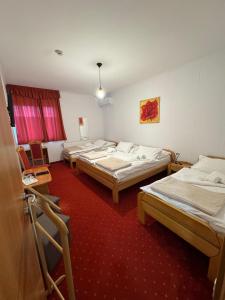 a room with three beds in it with a red carpet at Euro Panzio in Debrecen