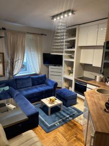 a living room with a blue couch and a kitchen at Lux Beba Pancevo in Pančevo