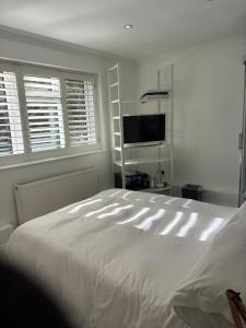 a bedroom with a large white bed and a flat screen tv at Mayfield guest rooms in Bromley