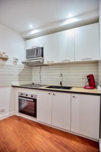 a kitchen with white cabinets and a sink and a microwave at Tranokely II in Antananarivo