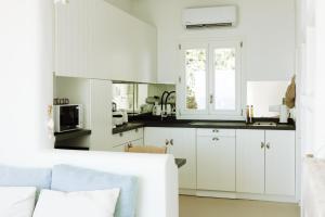 a kitchen with white cabinets and a white couch at Villa Riza in Apróvaton