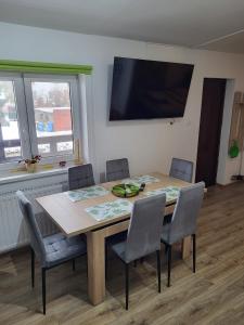 a dining room table with chairs and a television on the wall at Pokoje U Anny i Łukasza in Swornegacie