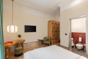a bedroom with a bed and a desk and a toilet at The Couper Umiltà in Rome +85 photos