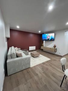 a living room with a couch and a flat screen tv at Logement entier avec jacuzzi proche futuroscope in Naintré