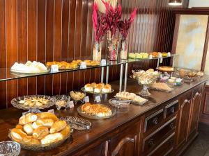 a buffet filled with different types of bread and pastries at Hotel Lenheiros in São João del Rei