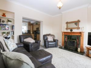 a living room with leather furniture and a fireplace at 3 Bay View Terrace in Llandudno