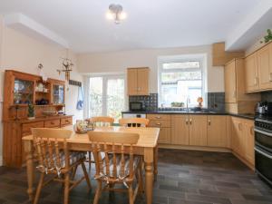 a kitchen with wooden cabinets and a wooden table and chairs at 3 Bay View Terrace in Llandudno
