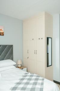 a white bedroom with a bed and a mirror at The Prestige Studio in Bloemfontein