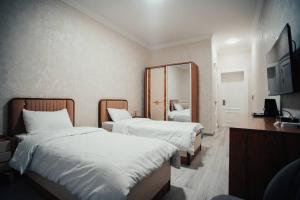 a hotel room with two beds and a mirror at Bog’ishamol Hotel Urgut in Min-Bulak