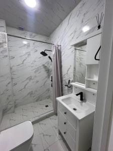 a white bathroom with a shower and a sink at Bog’ishamol Hotel Urgut in Min-Bulak