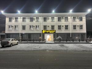 a white building with a car parked in front of it at Bog’ishamol Hotel Urgut in Min-Bulak