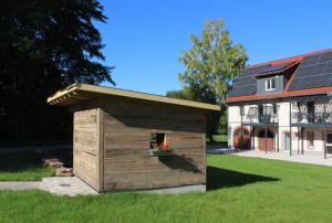 a wooden dog house in front of a house at Glöckle Mühle, Ferienwohnungen und Camping mit Sauna in Herbolzheim