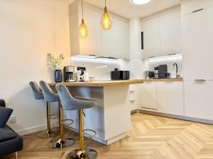 a kitchen with white cabinets and a counter with stools at Jarzebinowa Loft III by JumpInHere in Nowy Dwór Mazowiecki