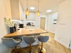 a kitchen with a counter and two stools at Jarzebinowa Loft III by JumpInHere in Nowy Dwór Mazowiecki +3 photos