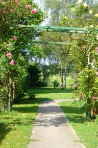 a garden with an arch with pink flowers and a pathway at Le Logis d Orgeval in Orgeval