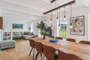 a dining room with a large wooden table and chairs at Holstvej 21 Holiday Home For 12 Guests With An Extra Bonus in Blokhus