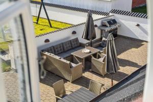a view of a patio with a couch and an umbrella at Holstvej 21 Holiday Home For 12 Guests With An Extra Bonus in Blokhus +4 photos