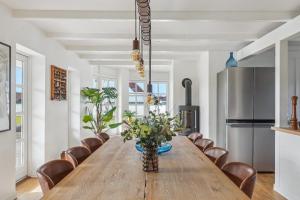 a dining room with a long wooden table and chairs at Holstvej 21 Holiday Home For 12 Guests With An Extra Bonus in Blokhus