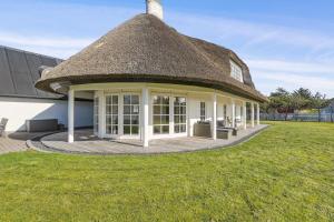 a thatch roofed house with a grass yard at Holstvej 21 Holiday Home For 12 Guests With An Extra Bonus in Blokhus