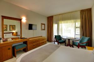 a hotel room with a bed and a table and chairs at Pilanesberg Hotel in Boshoek +10 photos