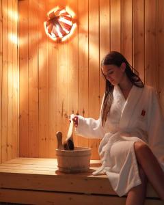 a woman sitting on a bench in a sauna at Rafaelo Deluxe Hotel & Spa Shengjin in Shëngjin